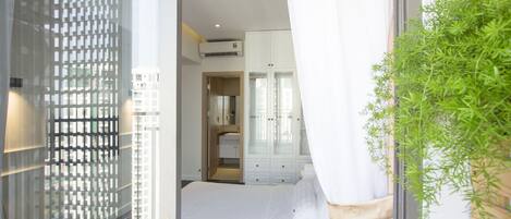 A bedroom with a bed, a wardrobe, and an air conditioning unit.