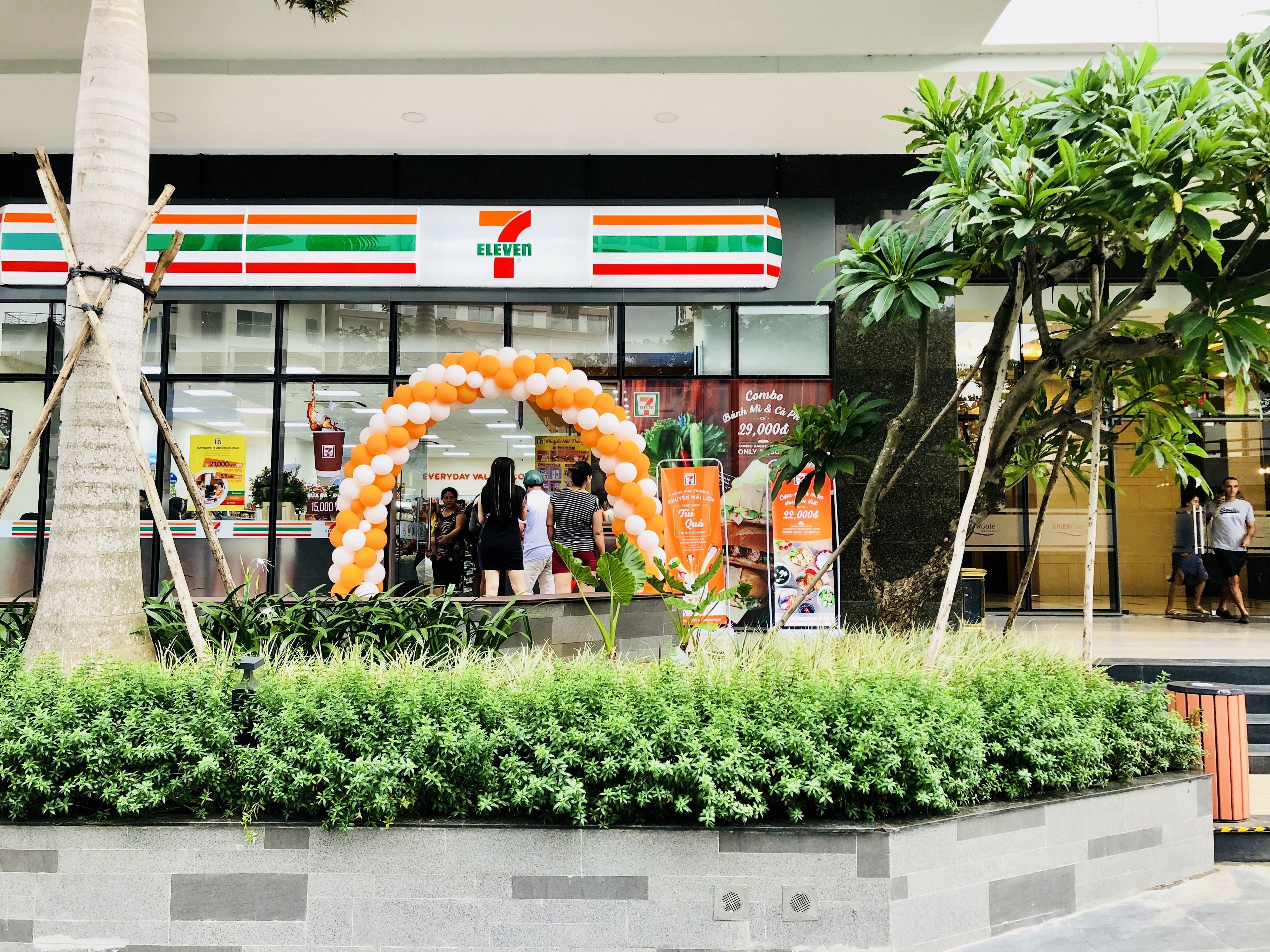 A 7-Eleven store with a large arch made of balloons.