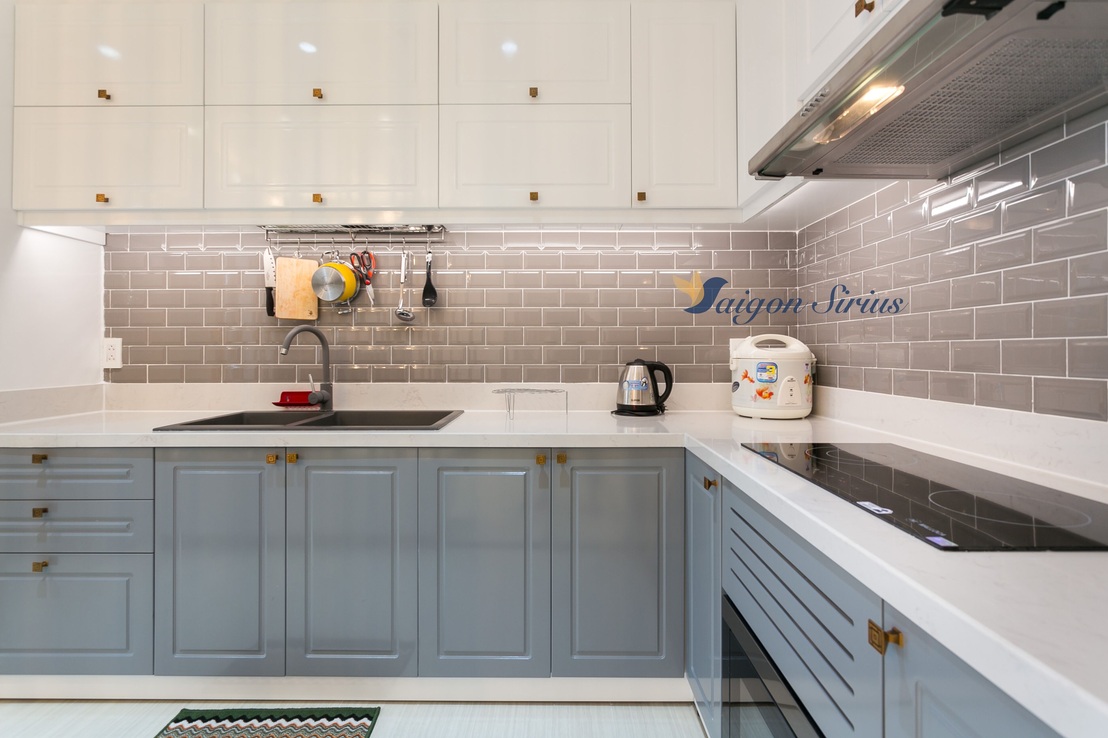 Una cocina moderna con armarios blancos, un lavamanos de acero inoxidable y un salpicadero de azulejos.
