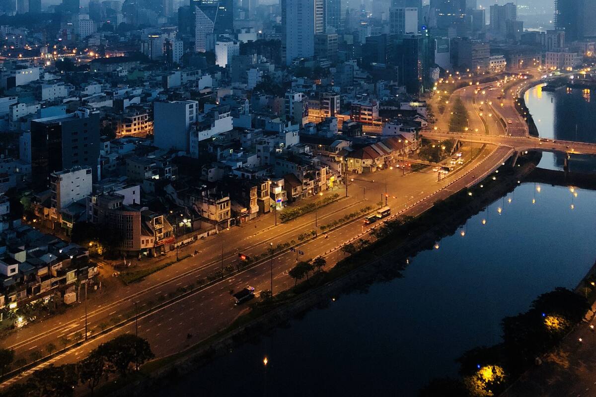 A cityscape at dusk with high-rise buildings and a river.