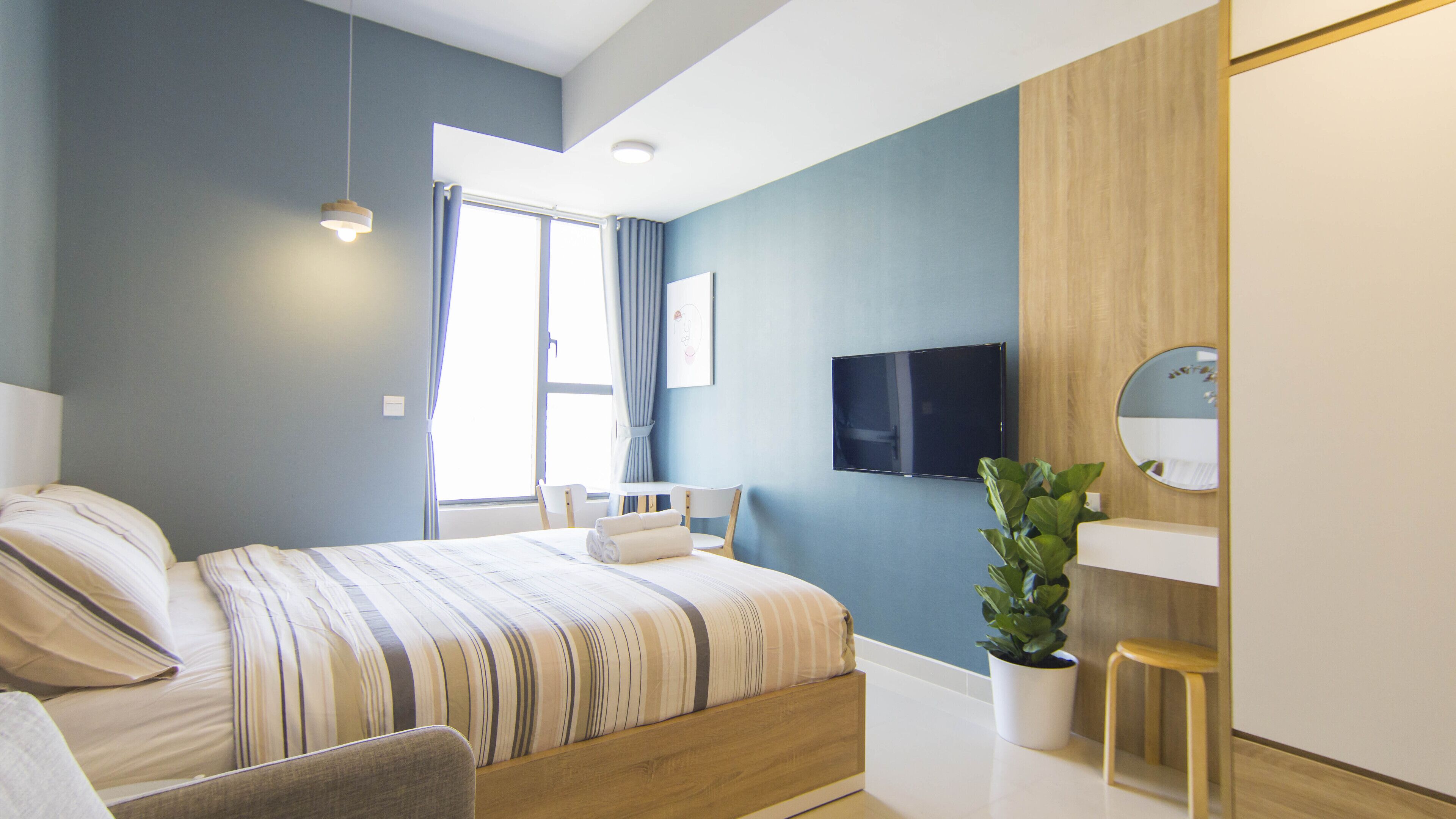 Ein modernes Schlafzimmer mit Bett, Nachttischen, einem Fernseher und einer Topfpflanze.