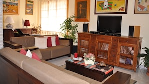 Ein Wohnzimmer mit Sofa, Fernseher, Schrank und einer Pflanze.