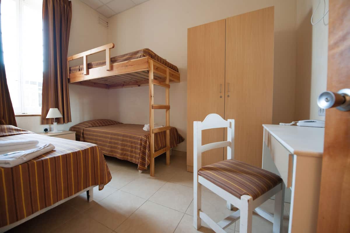 Un dormitorio con literas, un escritorio, una silla y un armario.