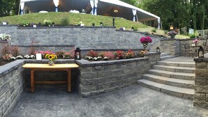 A stone retaining wall with steps leading up to a covered patio area. - Springside Inn (Auburn)