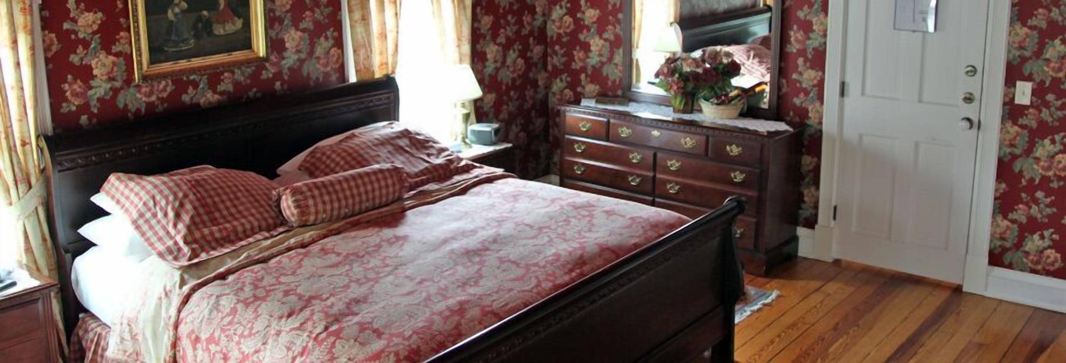 A bedroom with a bed, dresser, and a door.