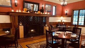 A dining area with a fireplace, wooden furniture, and a patterned rug. - Springside Inn (Auburn)