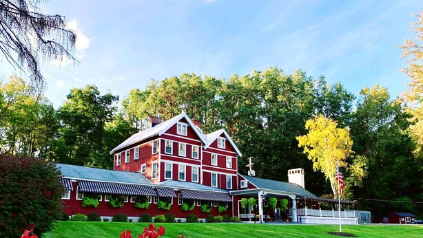A large, red, two-story building with a covered porch and a lawn in the foreground. - Springside Inn (Auburn)
