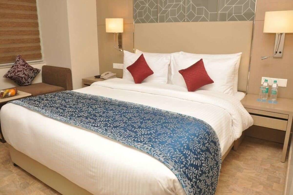 Ein Hotelzimmer mit einem großen Bett, einem Nachttisch, einem Sessel und einer Wandlampe.