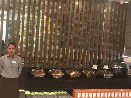 Buffet montado com várias estações de serviço e uma pessoa em frente.