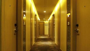 A hotel hallway with a geometric carpet pattern, wooden doors, and a warm yellow lighting. - Days Hotel by Wyndham Jaipur Tonk Road (Jaipur)