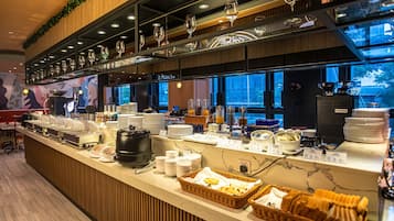 A buffet counter with various food items, a coffee machine, and a wine glass display.