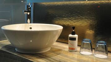 A bathroom sink with a large basin, a soap dispenser, and two glass containers.