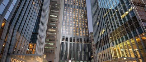 A modern high-rise building with a glass facade, surrounded by other tall buildings.