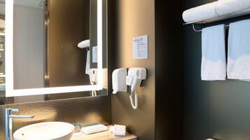 A modern bathroom with a large mirror, a sink, a toilet, and a towel rack.