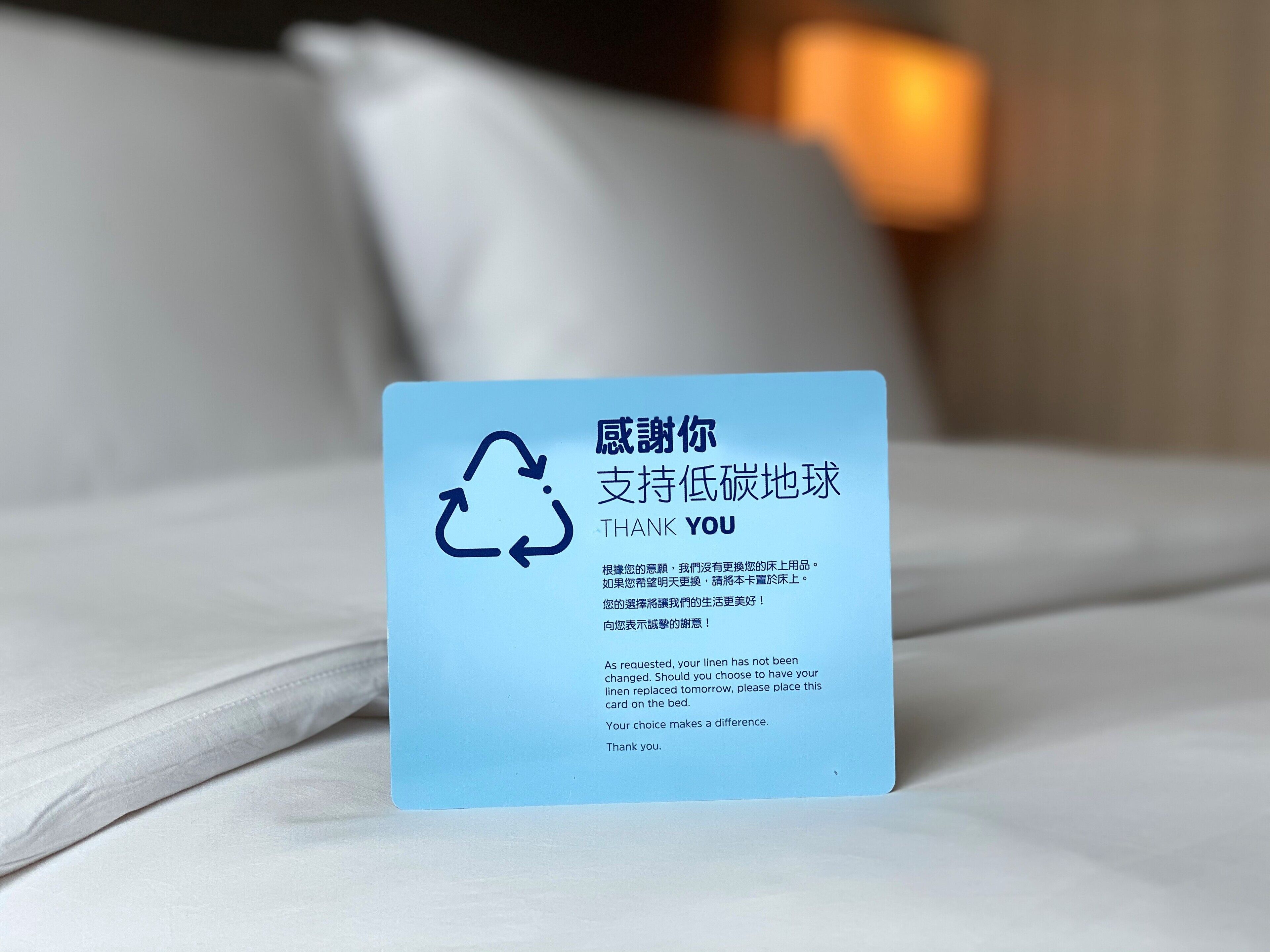 A thank you card on a bed with a recycling symbol.
