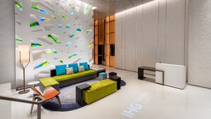 Un lobby moderno con diseño geométrico en la pared, un sofá verde y una recepción.
