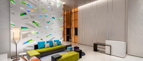 A modern lobby with a geometric wall design, a green sofa, and a reception desk.