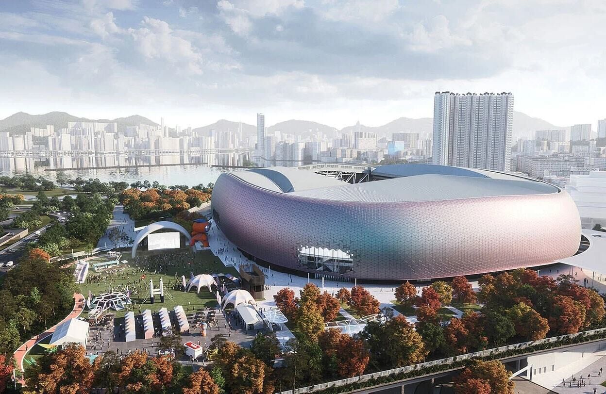 Un stade moderne doté d’une structure en forme de dôme unique, entouré d’un espace paysager agrémenté d’arbres et de sentiers.