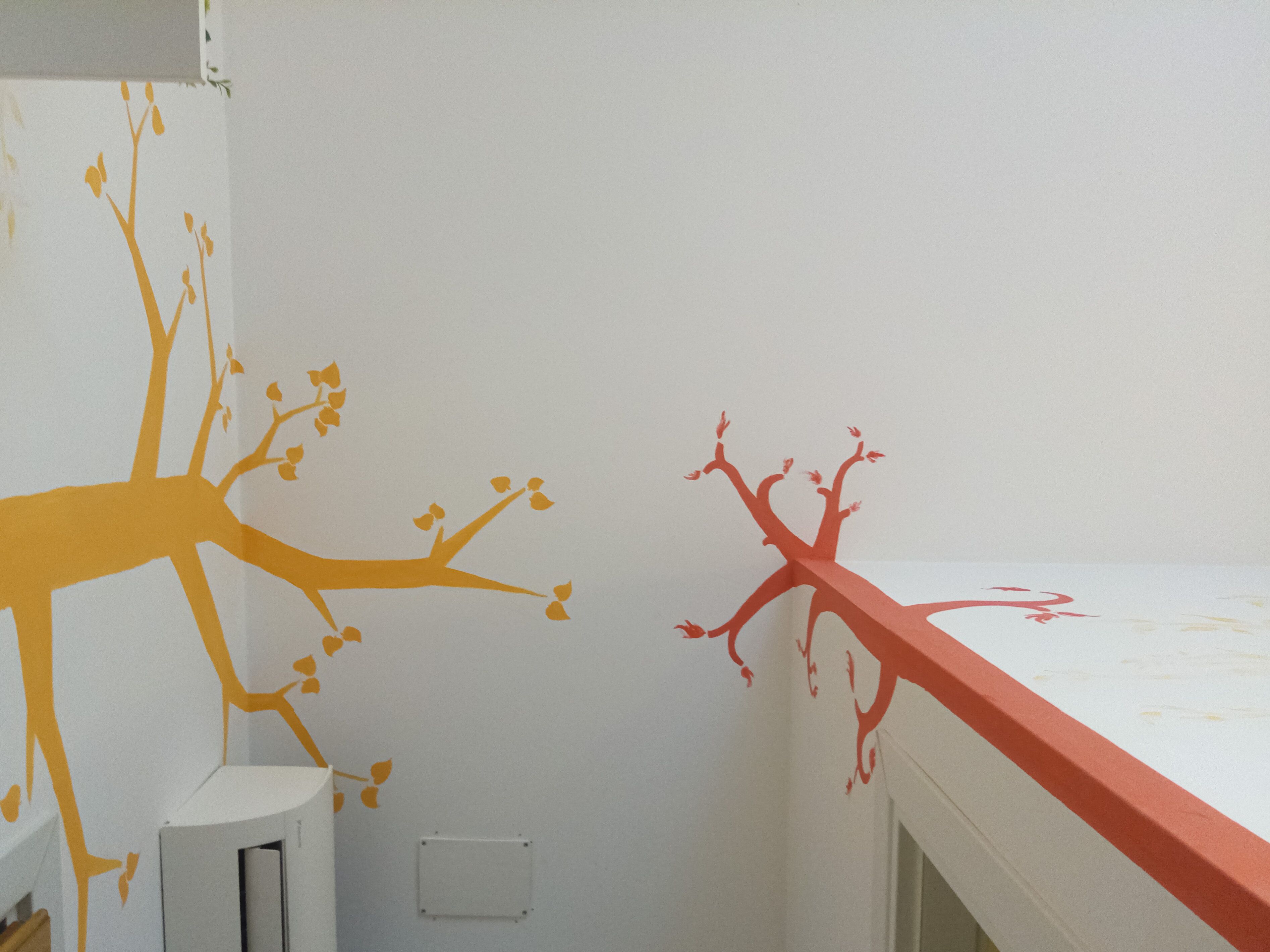 A room with a white wall featuring a tree decal in orange and red colors.