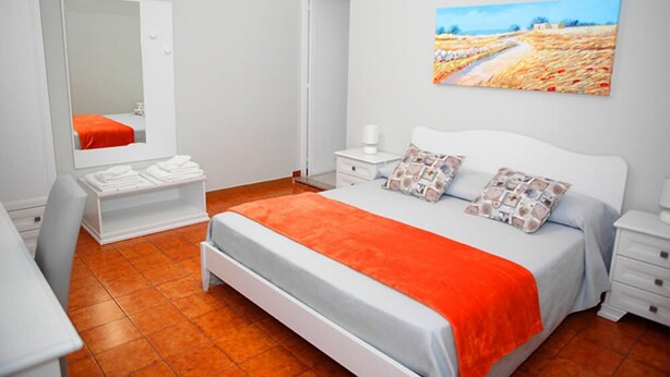 A bedroom with a bed, a bedside table, a nightstand, a mirror, a dresser, and a painting on the wall. - Le Stanze di Lucia (Tricase)