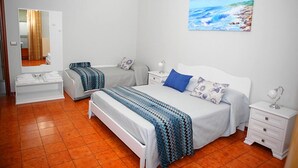 A bedroom with two beds, a large painting of a beach, and a white nightstand with a lamp. - Le Stanze di Lucia (Tricase)