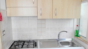 A compact kitchen with a gas stove, a sink, and wooden cabinets. - Le Stanze di Lucia (Tricase)