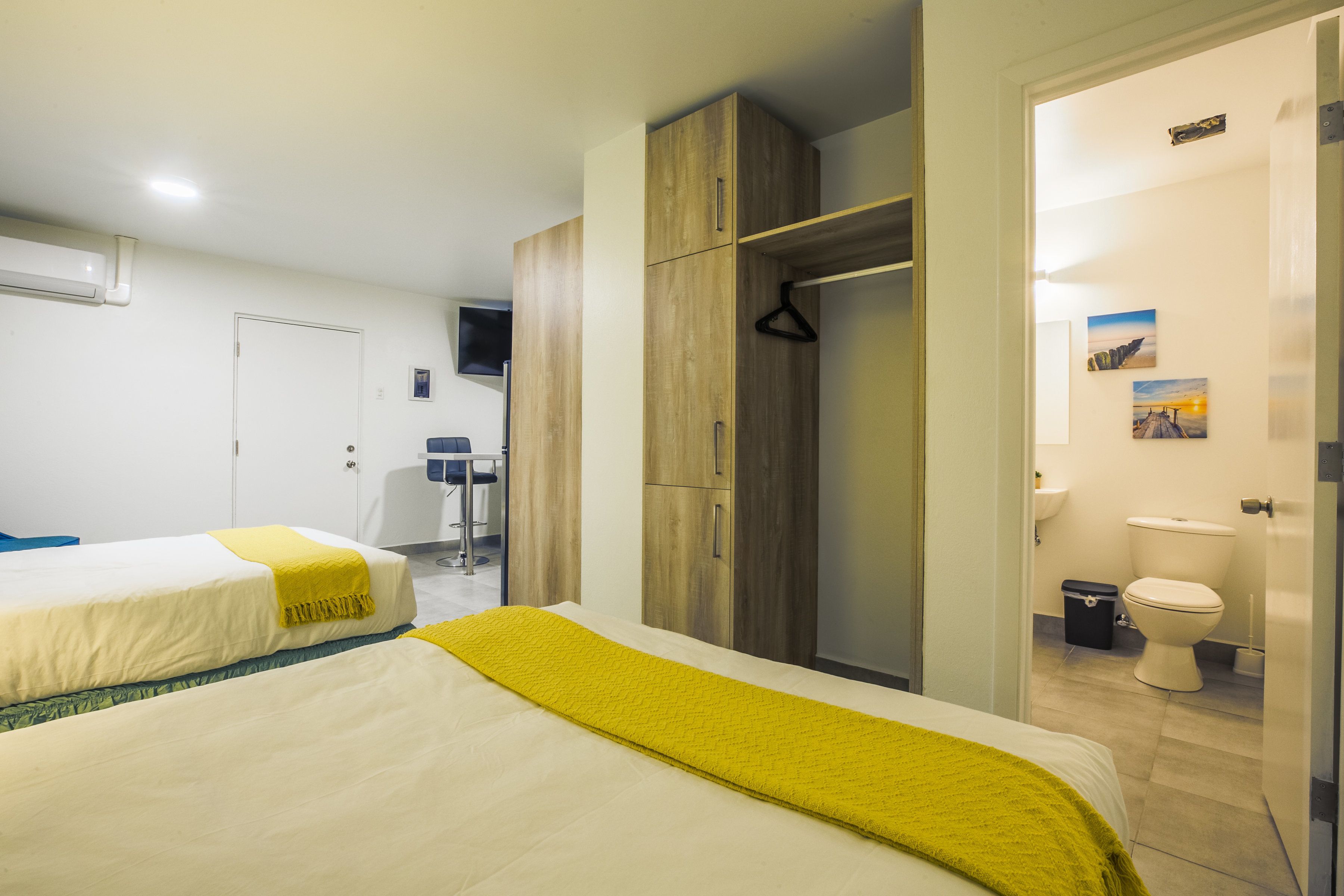 A hotel room with two beds, a wardrobe, a bathroom, and a television.