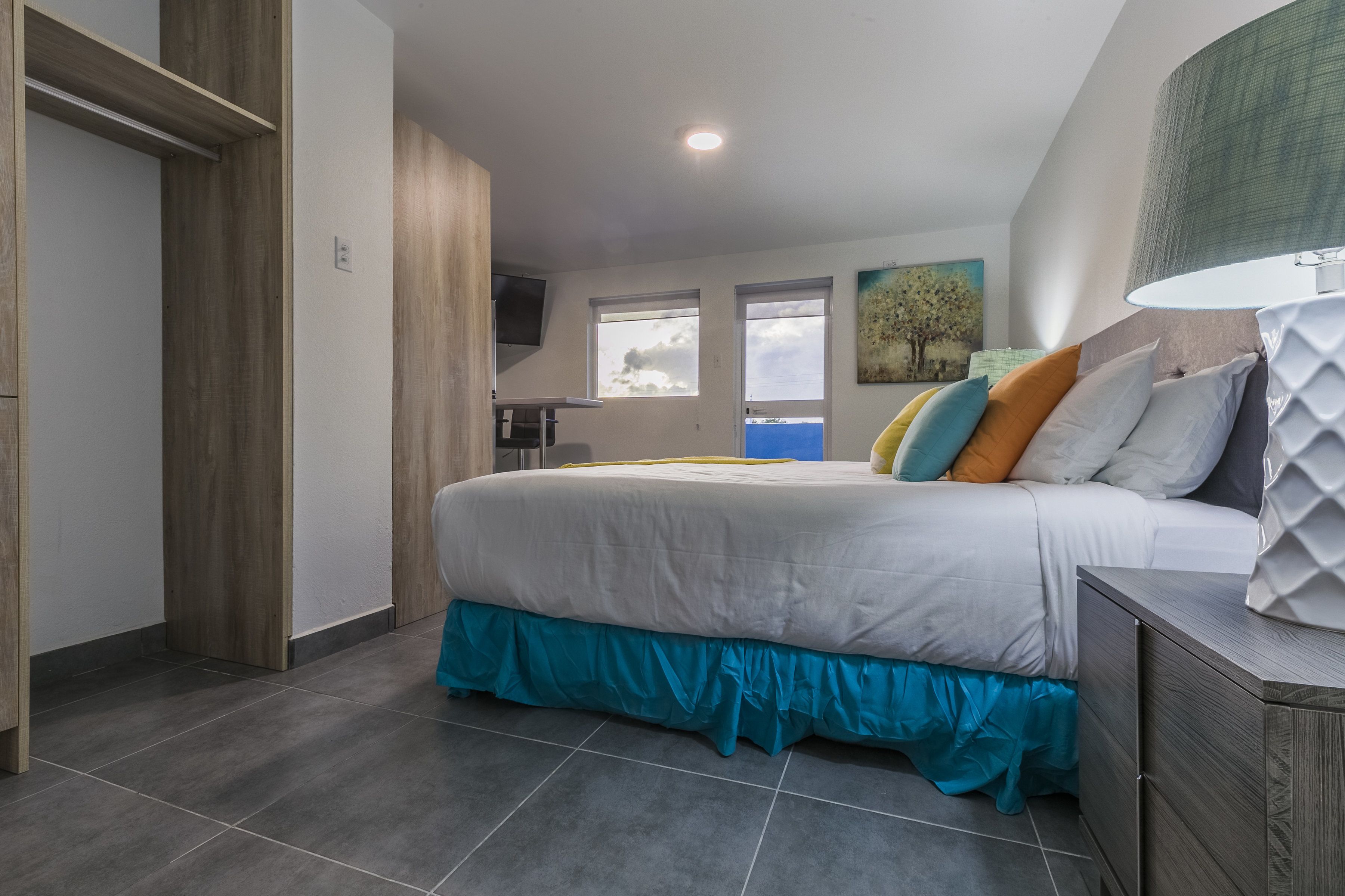 Une chambre à coucher avec un lit, une table de chevet, une lampe et une fenêtre.