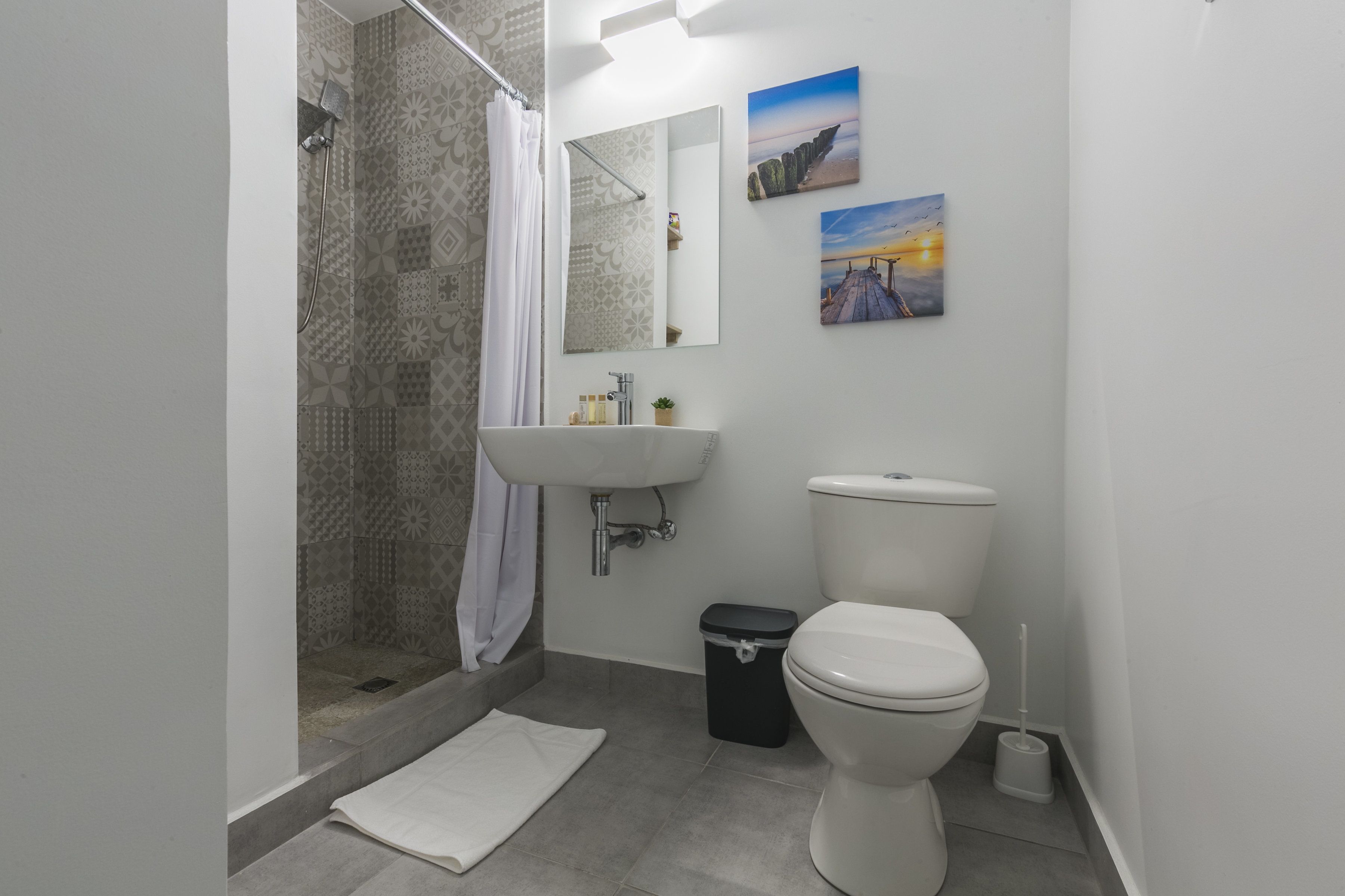 Ein modernes Badezimmer mit Dusche, Toilette, Waschbecken und zwei Bildern an der Wand.