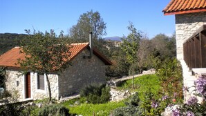 Un bâtiment en pierre surmonté d’un toit de tuiles rouges, entouré de verdure et sous un ciel bleu clair.
