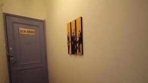 A hallway with a closed door and a sign that reads "BEI-VINDO". There are three framed pictures on the wall. - GoHouse Vergueiro 901 (Rio de Janeiro)