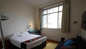 A hotel room with a bed, a desk, a chair, and a window with curtains. - GoHouse Vergueiro 901 (Rio de Janeiro)