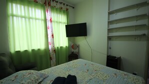 Ein Zimmer mit einem Bett, einem an der Wand befestigten Flachbildfernseher und einer an der Wand stehenden Schrankwand.
