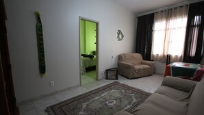Ein Wohnzimmer mit beiger Couch, einem gemusterten Teppich, einer grünen Wand und einer Tür zu einem anderen Raum.