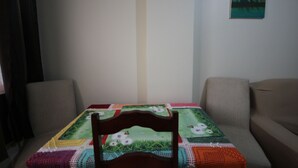 Ein Zimmer mit einem Tisch, der mit einer bunten Tischdecke bedeckt ist, zwei Stühlen und einem Bild an der Wand.