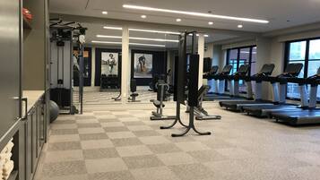 A gym with treadmills, weight machines, and a mirrored wall.
