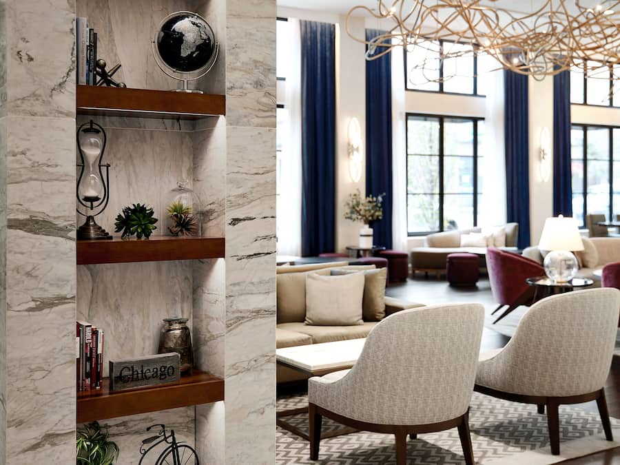 A modern living room with a marble column, wooden shelves, and a unique chandelier.