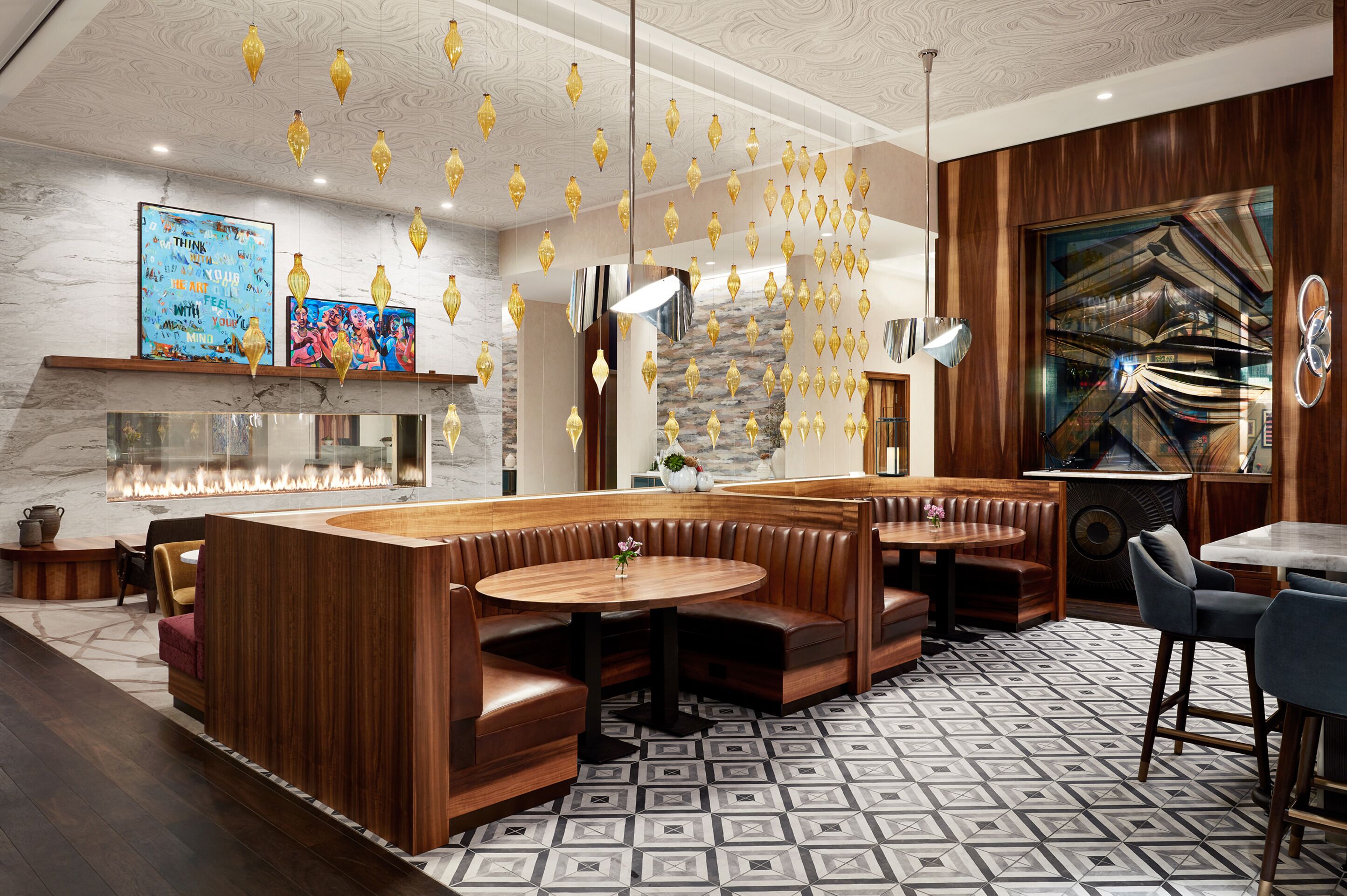 A modern interior with a central seating area, a fireplace, and decorative hanging lights.