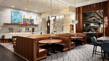 A modern interior with a central seating area, a fireplace, and decorative hanging lights.