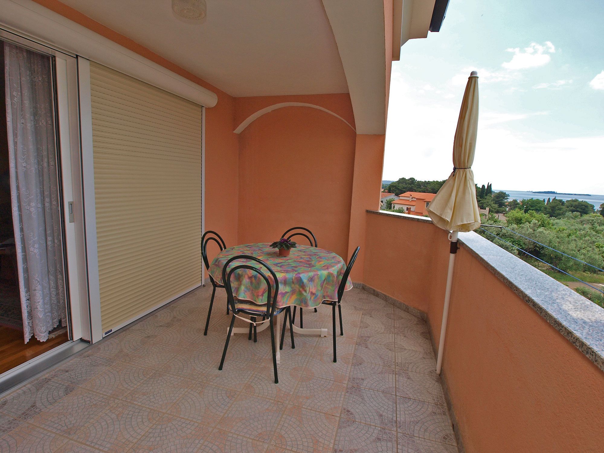 A balcony with a table and chairs, a sliding door, and a view of the landscape.
