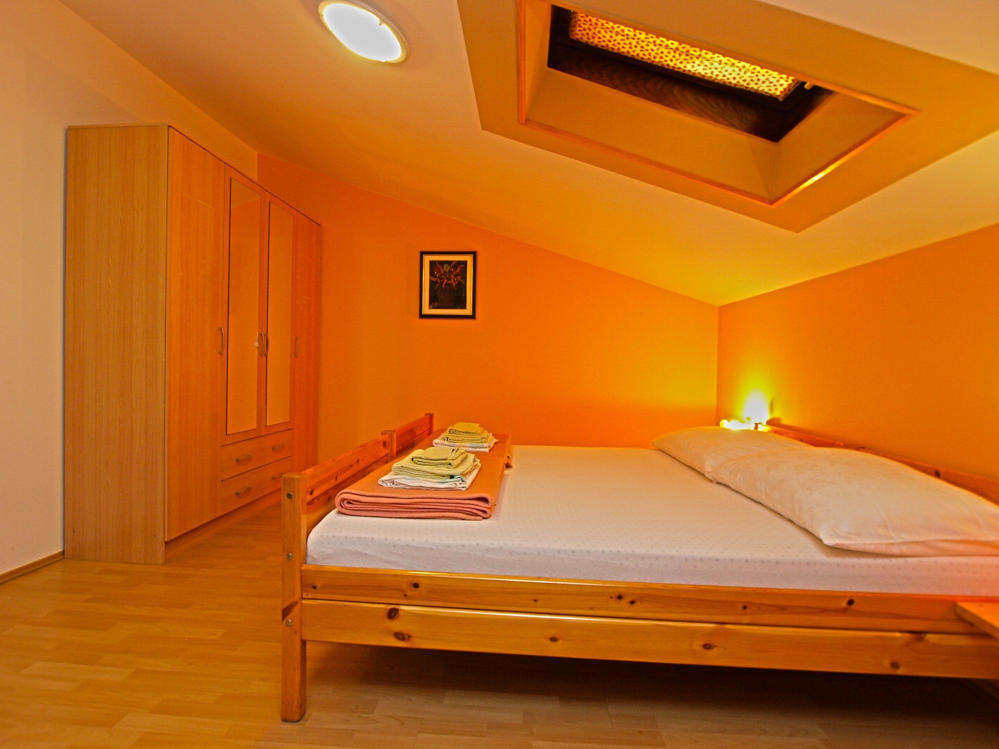 A bedroom with a wooden bed, a wardrobe, and a ceiling light fixture.