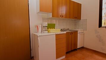 A compact kitchen with wooden cabinets, a white refrigerator, a coffee maker, and a sink.