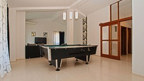 A spacious room with a pool table, a television, and a door leading to another area. - Apartment Marija 85 (Fazana)