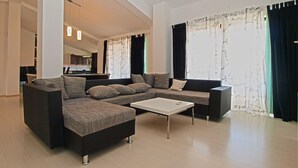 A modern living room with a sectional sofa, a coffee table, and a dining area in the background. - Apartment Marija 85 (Fazana)