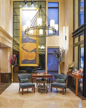 A lobby with a large chandelier, two armchairs, a coffee table, and a large abstract painting on the wall. - Millennium Istanbul Golden Horn (Istanbul)