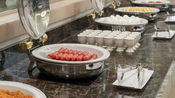 A buffet setup with various dishes including sausages, eggs, and other food items.