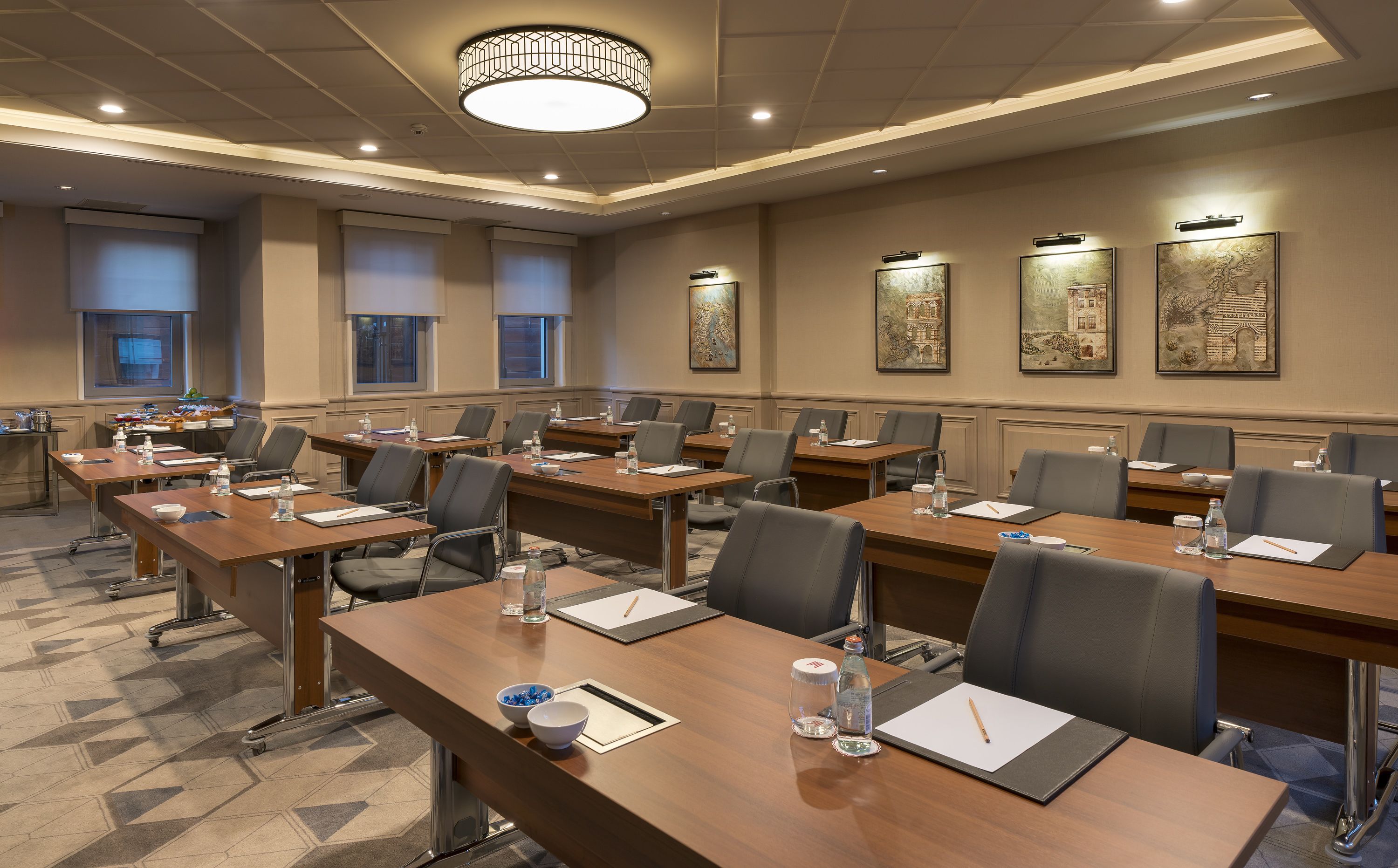 A conference room with multiple tables, chairs, and a large chandelier.