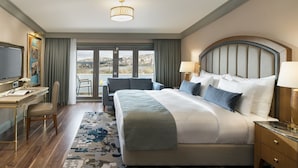 A hotel room with a large bed, a desk, a chair, a TV, and a view of the city through the window. - Millennium Istanbul Golden Horn (Istanbul)
