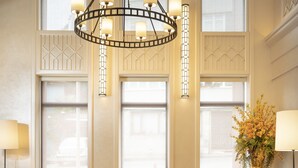 A spacious room with a large brown sofa, two yellow armchairs, a round coffee table, and a decorative chandelier. - Millennium Istanbul Golden Horn (Istanbul)