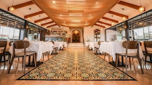A restaurant with a long, patterned carpet leading to a bar area, wooden ceiling beams, and large windows. - Millennium Istanbul Golden Horn (Istanbul)